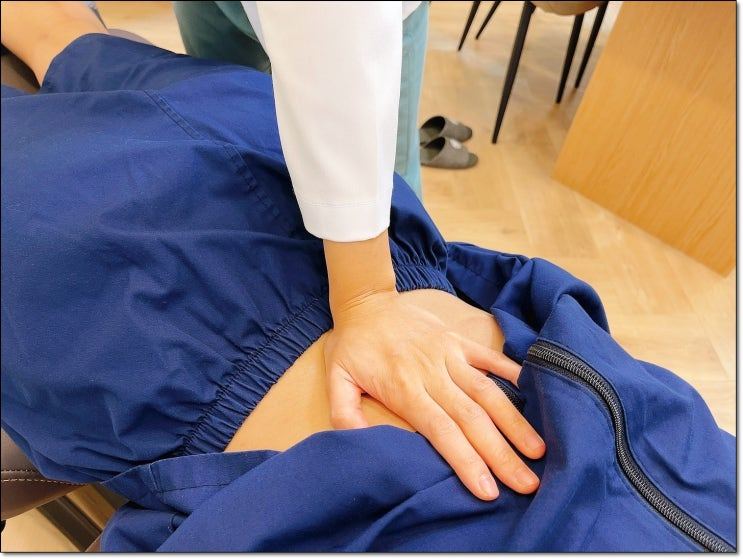 옆으로 누운 환자의 허리를 손으로 누르는 모습