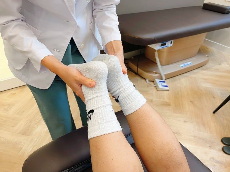 의료진이 누운 환자의 양쪽 무릎을 잡아 검사하는 사진